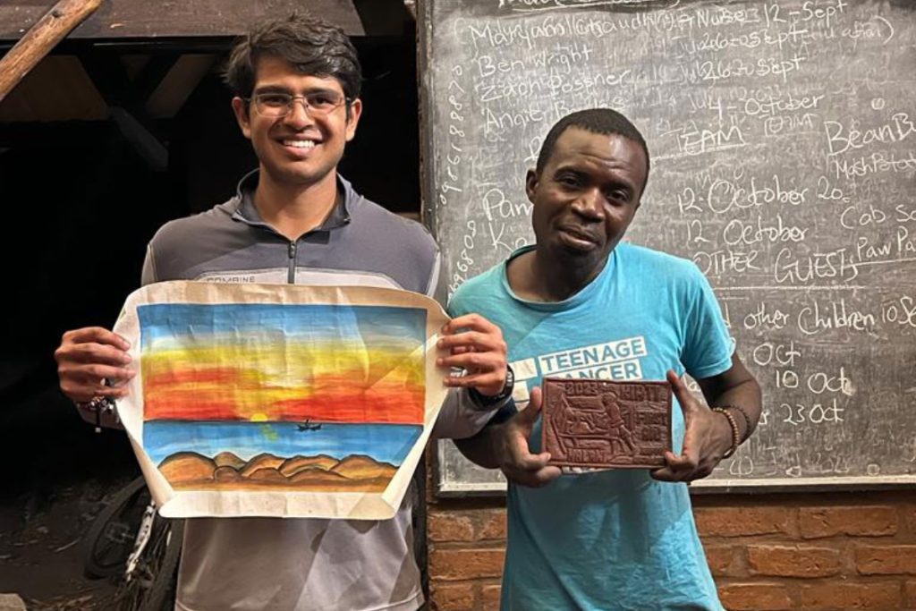 Volunteer Kirti stands with Faston who painted him the Mwaya sunrise in Malawi
