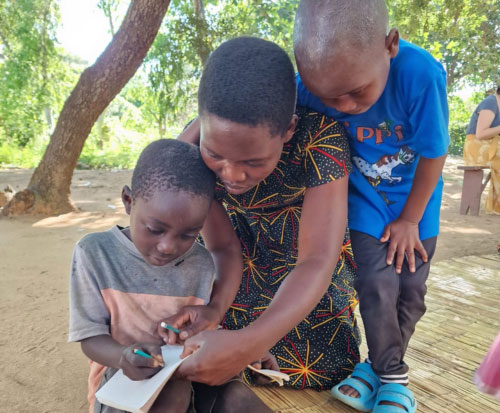 Preschool teacher Katy helps students with maths in Malawi