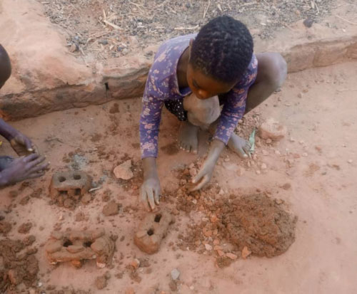 A child makes a mini cookstove in Malawi