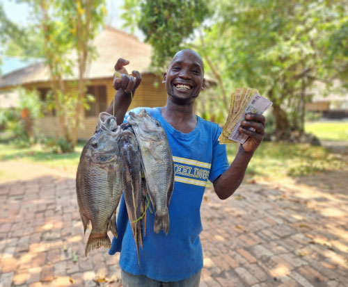 A fisherman with his catch and earnings in Malawi