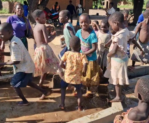 Happy splashing as the children enjoy the first water from their borehole in Malawi