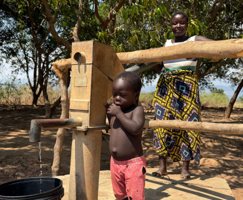 Mother and son pump water at a borehole in Malawi