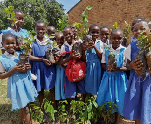 Students smiling with their fruit tree seedlings