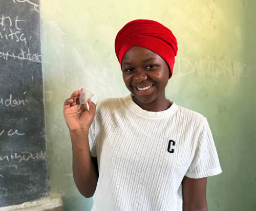 A schoolgirl smiling as she holds her new menstrual cup