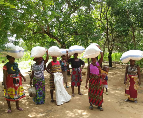 Ladies carrying bags of briquettes