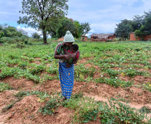 Niffa stood holding her daughter Jessy in her field