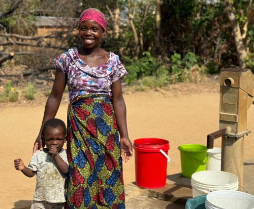 Irene Phiri with her child at the repaired borehole
