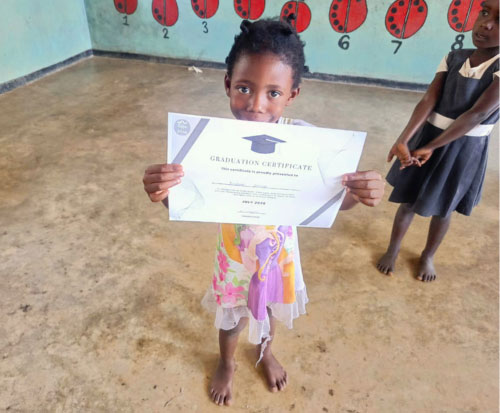 Preschool girl holding her graduation certificate