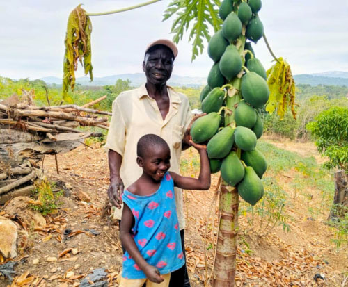 Fayida with his grandson with their papaya tree